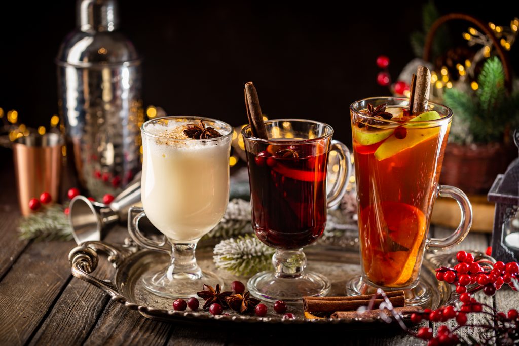 fresh yellow eggnog, grog and fruity red mulled wine with Christmas decoration. Selection of autumn or winter alcoholic hot drinks